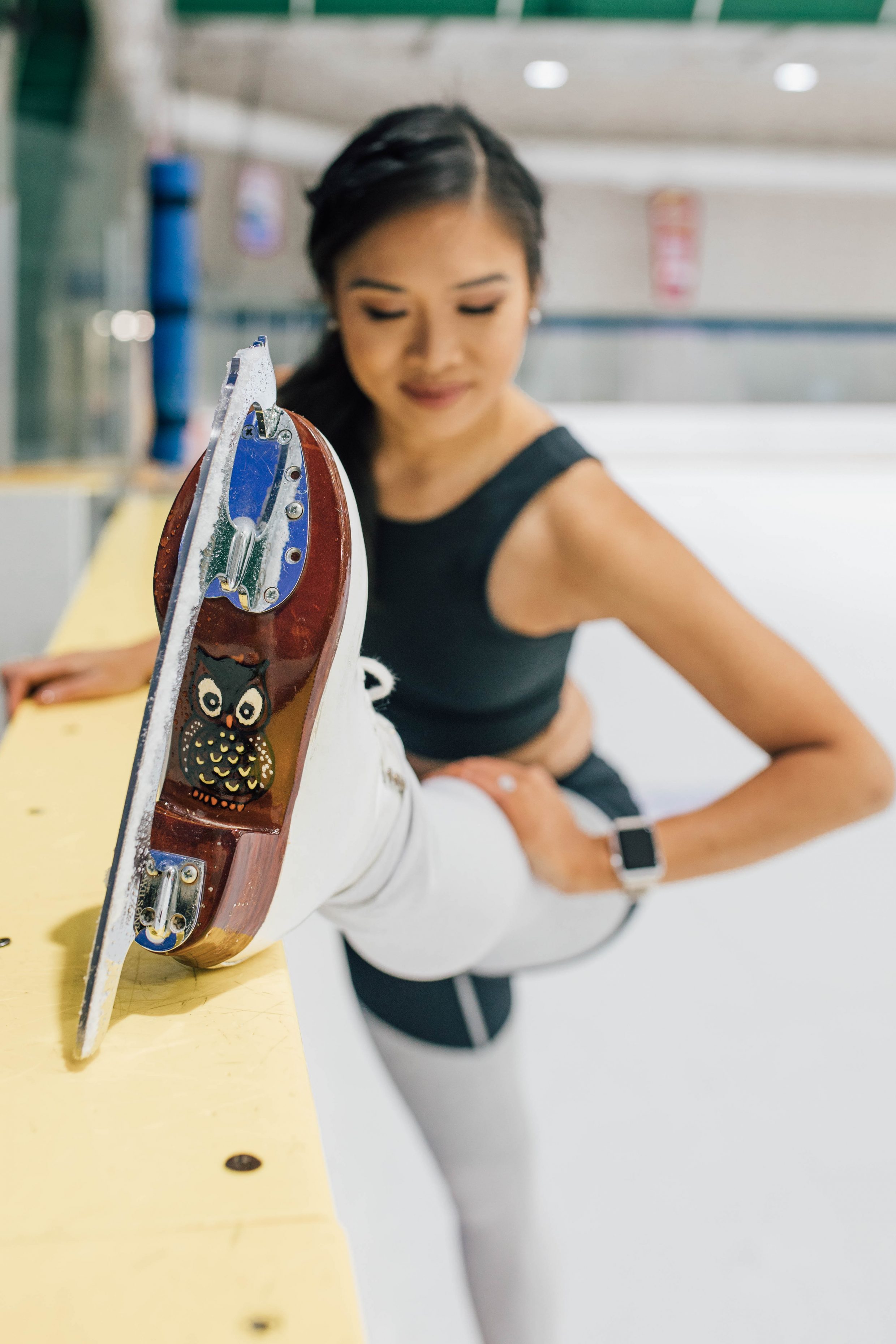 Hoang-Kim stretches by the board at the ice rink in her custom Harlick Skating Boots