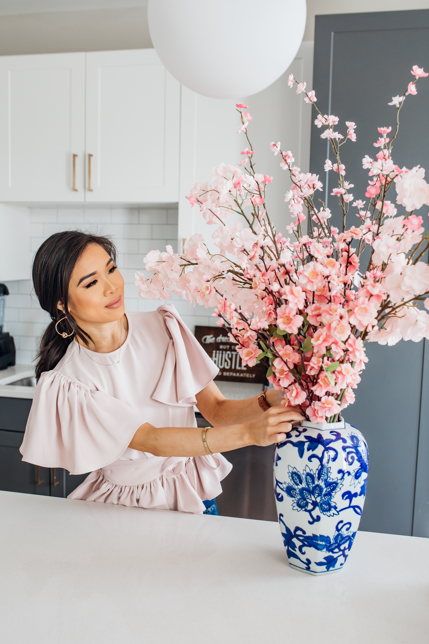 Hoang-Kim creates a faux cherry blossom and sakura arrangement using a ginger jar from At Home in her two-toned kitchen in Dallas, Texas