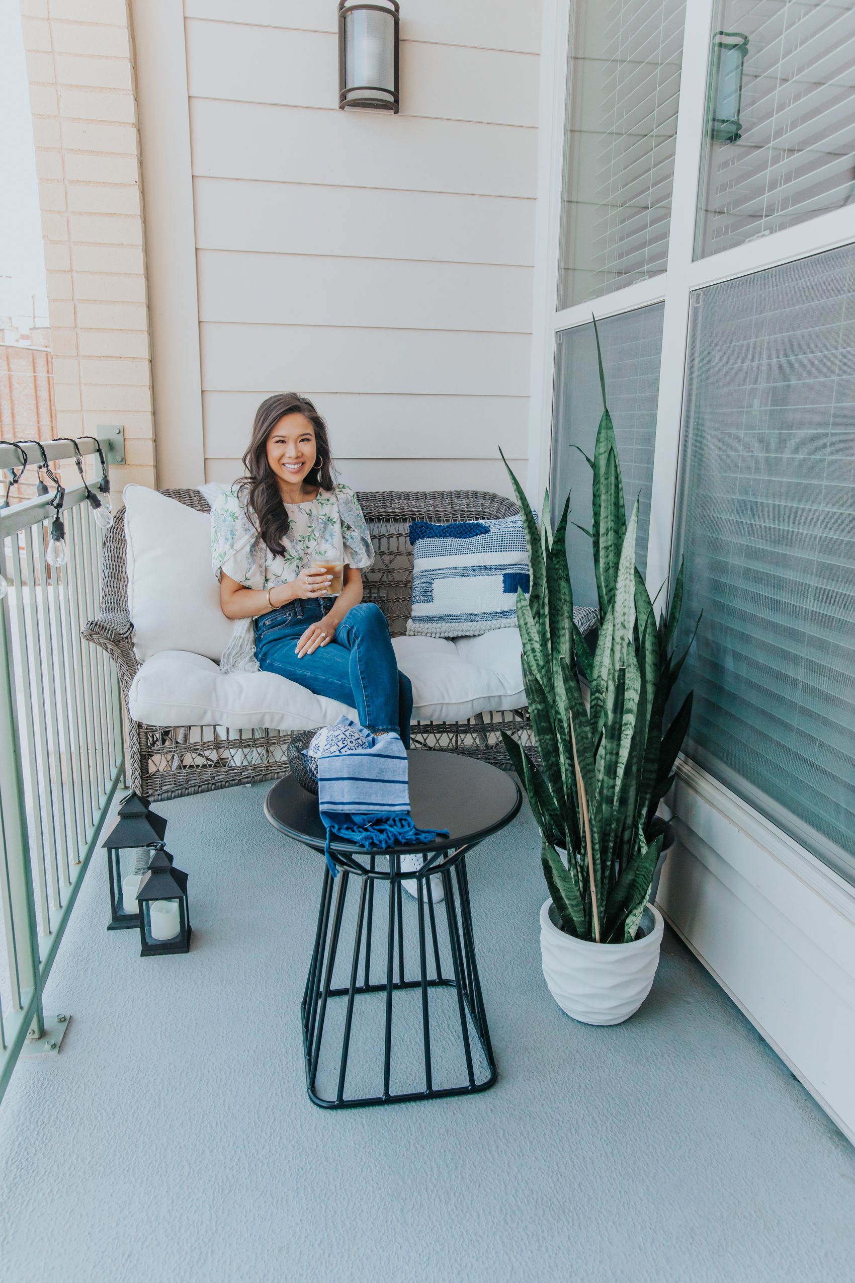Blogger Hoang-Kim in her small apartment balcony she transformed into an oasis with a wicker settee, snake plants, pillows, lanterns and more