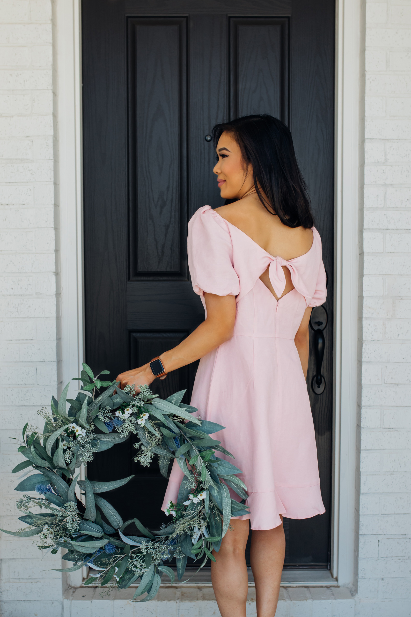 Blogger Hoang-Kim wearing a pink puff sleeve linen dress with a faux eucalyptus wreath 