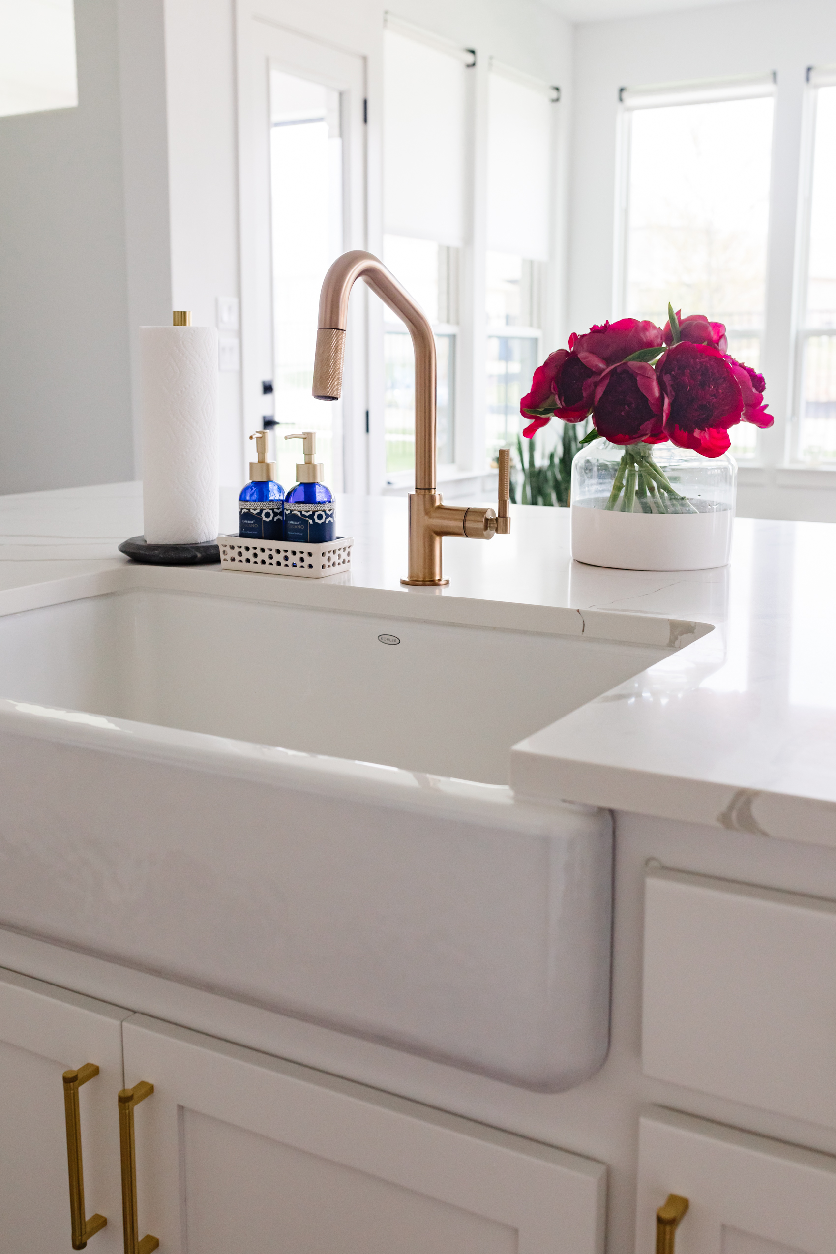 Brizo Litze Angled Pull Down faucet with knurled handle, Kohler Whitehaven farmhouse sink in a transitional kitchen, Serena & Lily poetto vase with red peonies