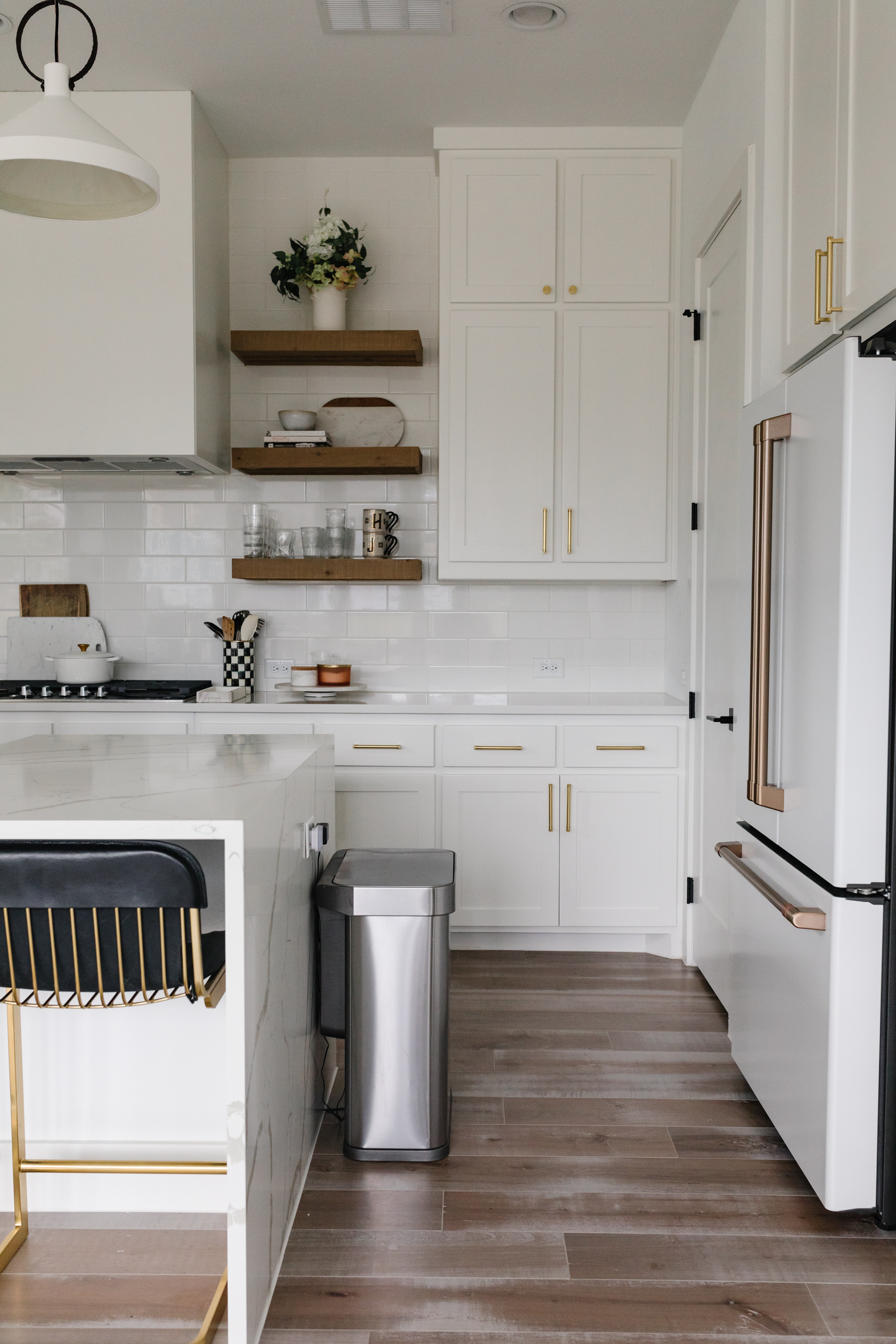 Transitional kitchen with brass Brizo faucet, McGee & Co Pendant lights, CB2 Barstools, Cafe Appliances Refrigerator, Rejuvenation West Slope hardware, MacKenzie-Childs utensil holder kettle and more