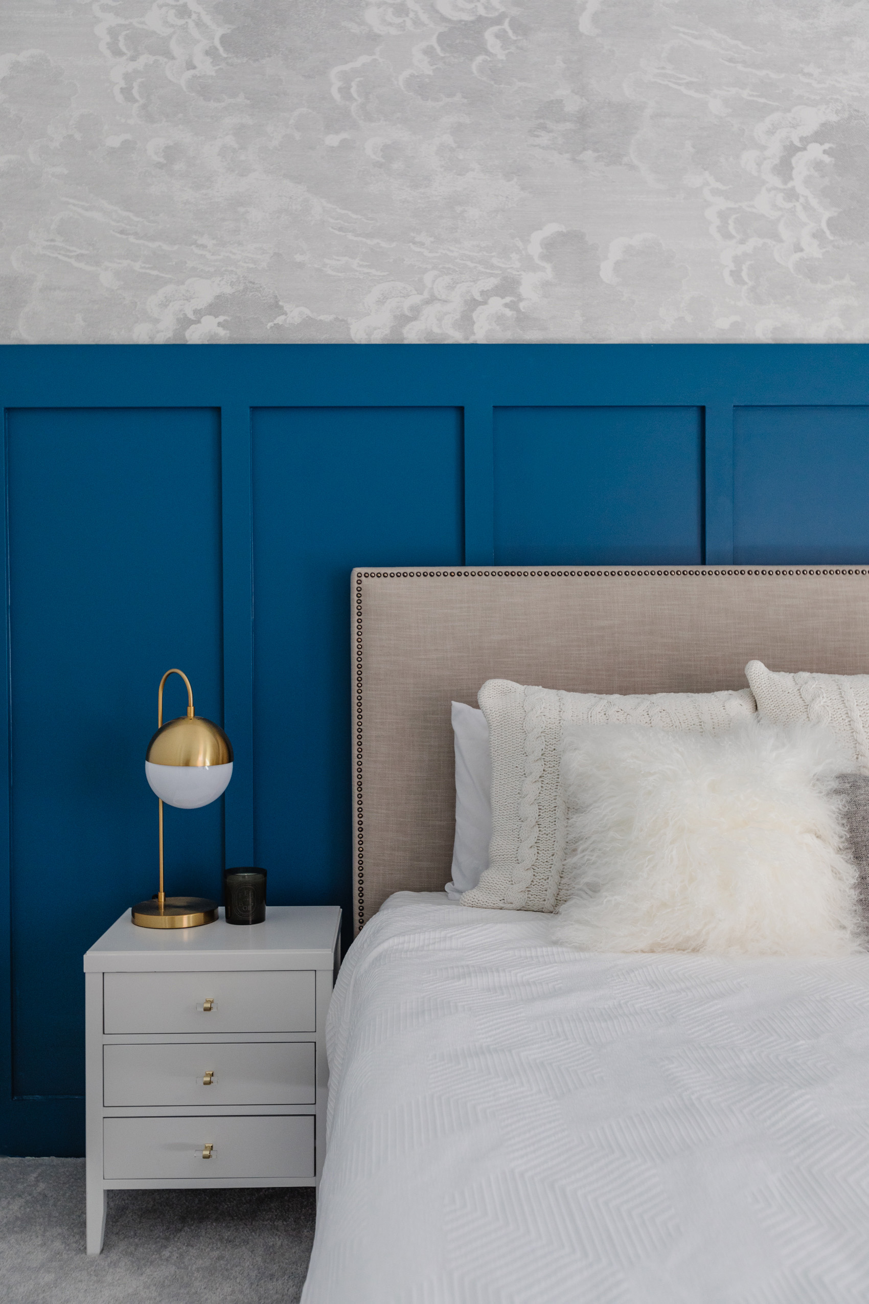 Chinese Porcelain board and batten wall with cloud wallpaper, west elm nailhead upholstered headboard, white nightstands, diptyque candle and white bedding
