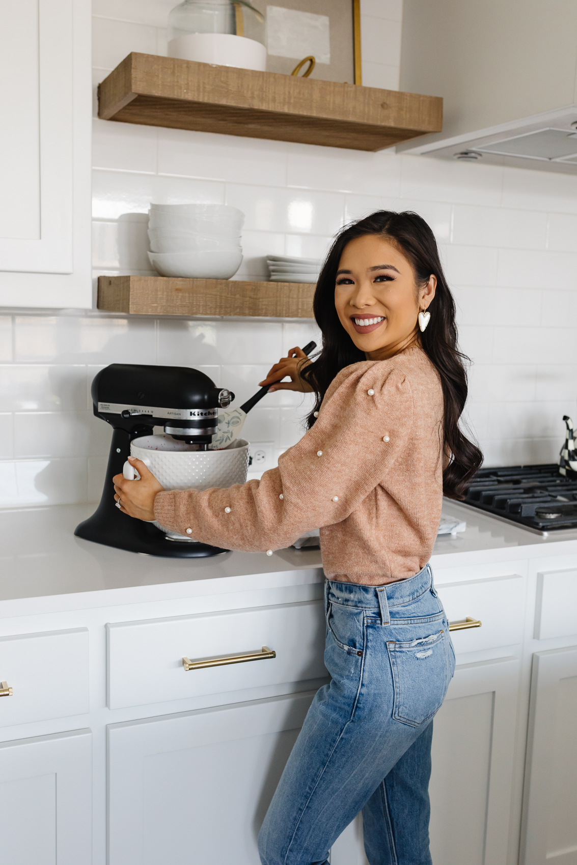Blogger Hoang-Kim wearing a pearl sleeve sweater, high waisted Mom jeans making a cake with her matte black Kitchenaid Stand mixer with hobnail bowl